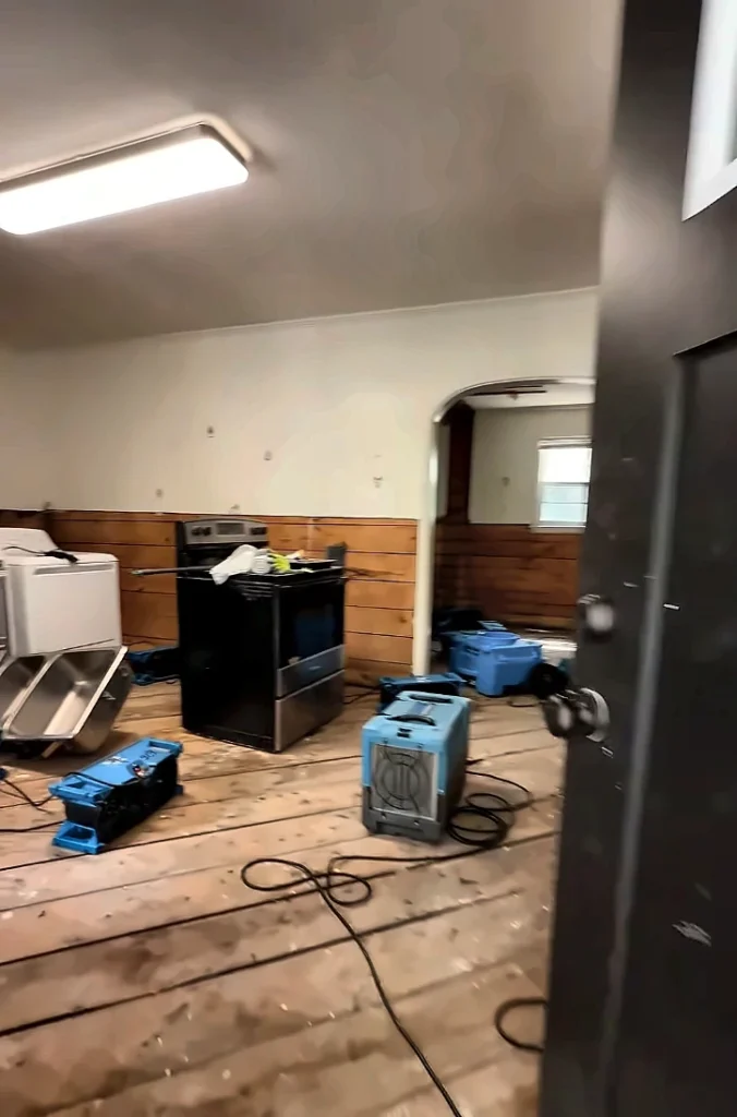 Water damage restoration company Estero FL: air movers and a dehumidifier drying a living room during water damage restoration
