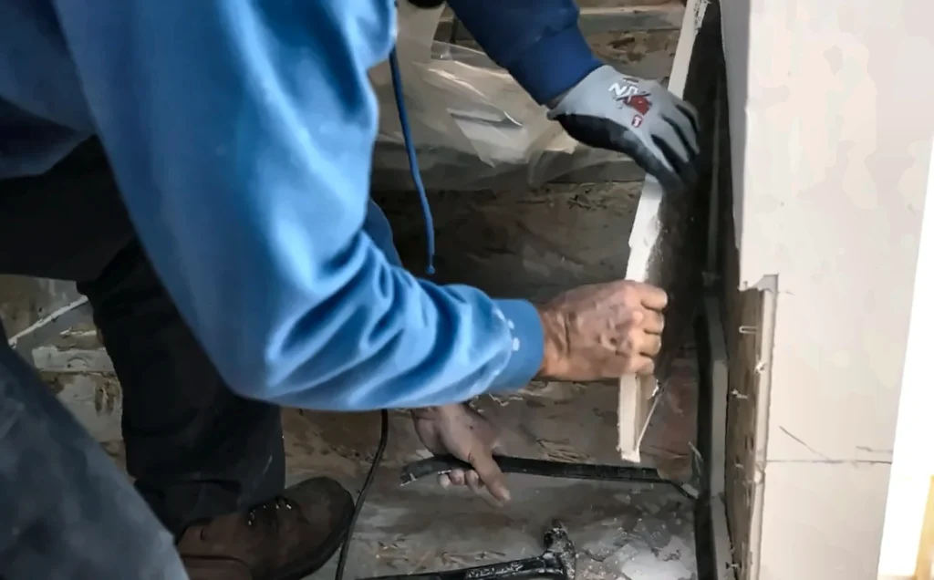 Technician removing a wet baseboard during mold remediation in Naples